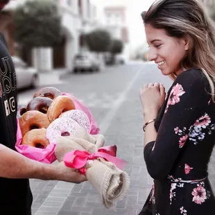 a woman holding a bunch of donuts