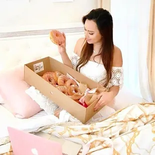 a woman holding a box of donuts