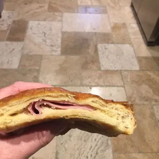 a hand holding a half eaten sandwich