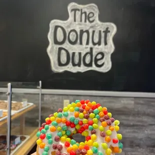 a hand holding a donut with sprinkles