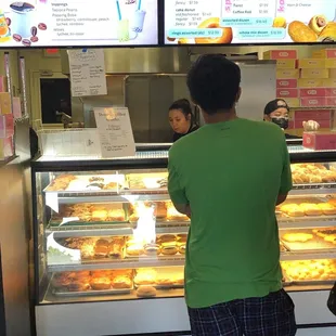 a woman standing in front of a display of donuts