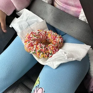a baby in a car seat with a donut in a wrapper
