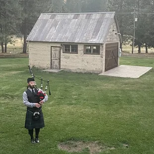 Bagpiper in front of the historic bathhouse that has been converted to an outdoor dining spot or chapel for weddings!