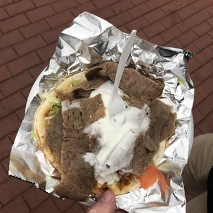 a person holding a sandwich wrapped in foil