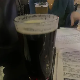 a woman sitting at a table with a glass of beer