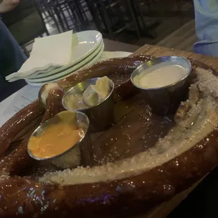 a large pretzel with dippings