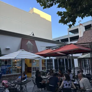 people sitting at tables under umbrellas