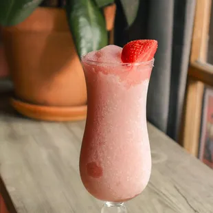 a pink drink with a strawberry garnish
