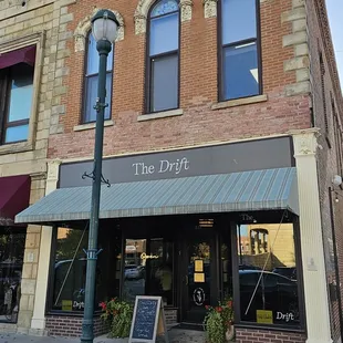 the front of a building with a sign on the sidewalk