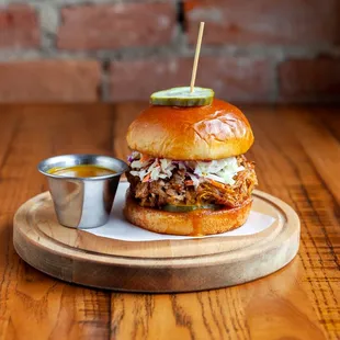 a pulled pork sandwich with pickles and coleslaw