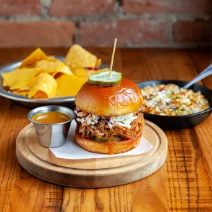 a pulled pork sandwich with a side of chips