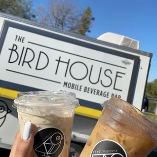 a person holding two cups of iced coffee