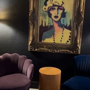 two chairs and a table in front of a painting