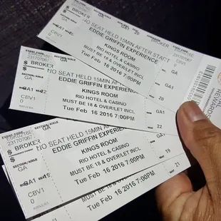 a hand holding three tickets