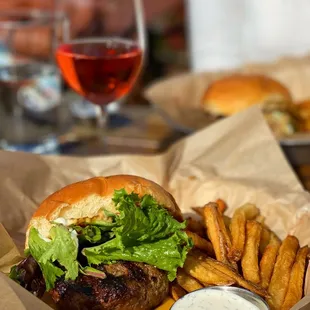 a burger and fries with a glass of wine