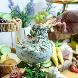a person dipping a dip into a glass bowl