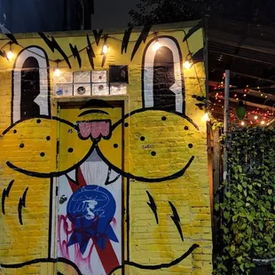 a yellow brick building with a painting on it