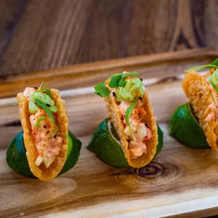 three tacos on a wooden tray