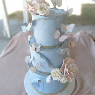 a three tiered cake with flowers and butterflies
