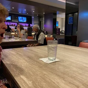 a woman sitting at a table with a glass of water in front of her