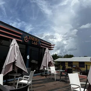 tables and chairs on a deck with umbrellas