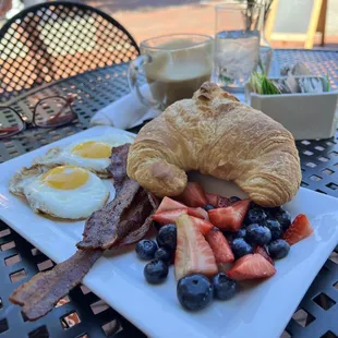 a croissant, bacon, strawberries, and eggs
