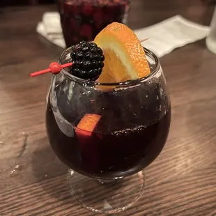 a glass of red wine with fruit garnish