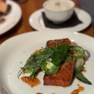 The salmon topped with mint and jalapeños with bok choy underneath it and rice in the background.