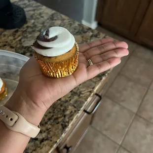 a hand holding a cupcake