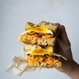 Breakfast Sandwich is made with pimento cheese, bacon or sausage, and a fried egg.