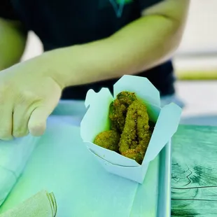 a person holding a tray of fried food