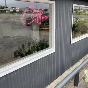 a coffee shop with a neon sign in the window