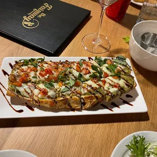 Caprese flatbread - pesto sauce, mozzarella, red onion, tomato, arugula, balsamic drizzle.