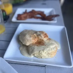 a plate of biscuits with gravy and bacon