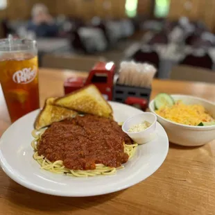 a plate of spaghetti, bread, and a drink
