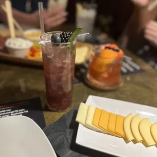 a plate of cheese, crackers, and a drink