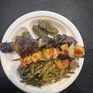 Shrimp and beef kebab dinner with stuffed grape leaves and seasoned green beans