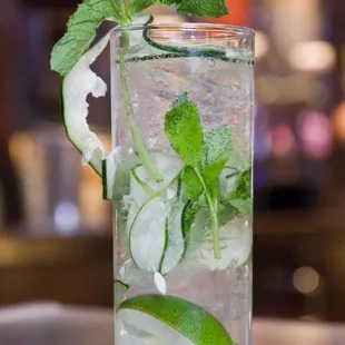 a glass of water with ice, cucumber and mint
