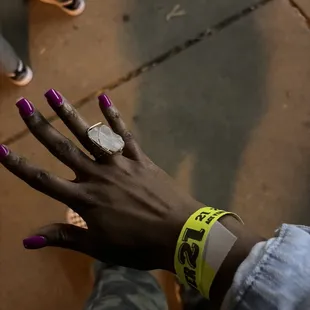 a woman&apos;s hand with purple nail polish