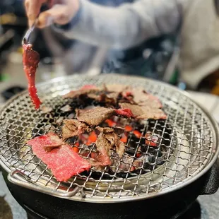 a person cooking steak on a grill