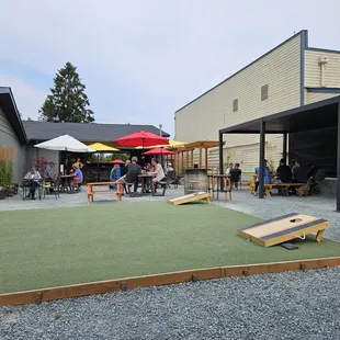 Gravel patio with covered seating, and corn hole and jumbo connect four.