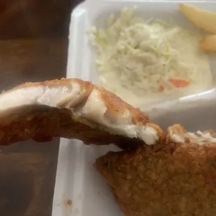 a piece of fried fish with a side of coleslaw