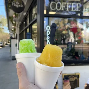 a hand holding two cups of ice cream