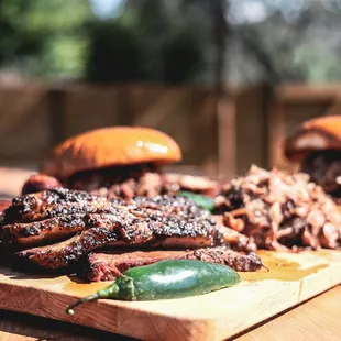 a wooden cutting board with meat and peppers on it