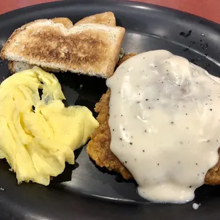 Chicken Fried Steak Breakfast with a hand breaded small chicken fried steak, smothered in gravy, two eggs (scrambled), and wheat toast.
