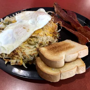Texas Hash Plate with Texas Hash (hashbrowns, jalapenos, grilled onions, melted cheese) topped with two eggs (over easy), and bacon.