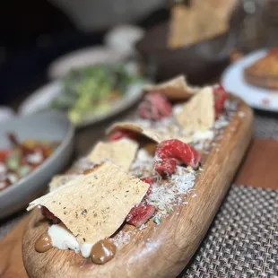 Black pepper charred filet mignon carpaccio with horseradish, shaved parmesan, black garlic aioli, and a house made herbed lavash.