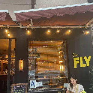 a woman sitting at a table outside a restaurant