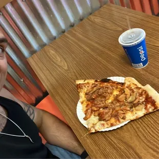 a man sitting at a table with a slice of pizza
