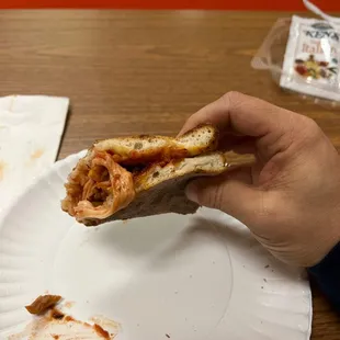 a hand holding a half eaten pizza